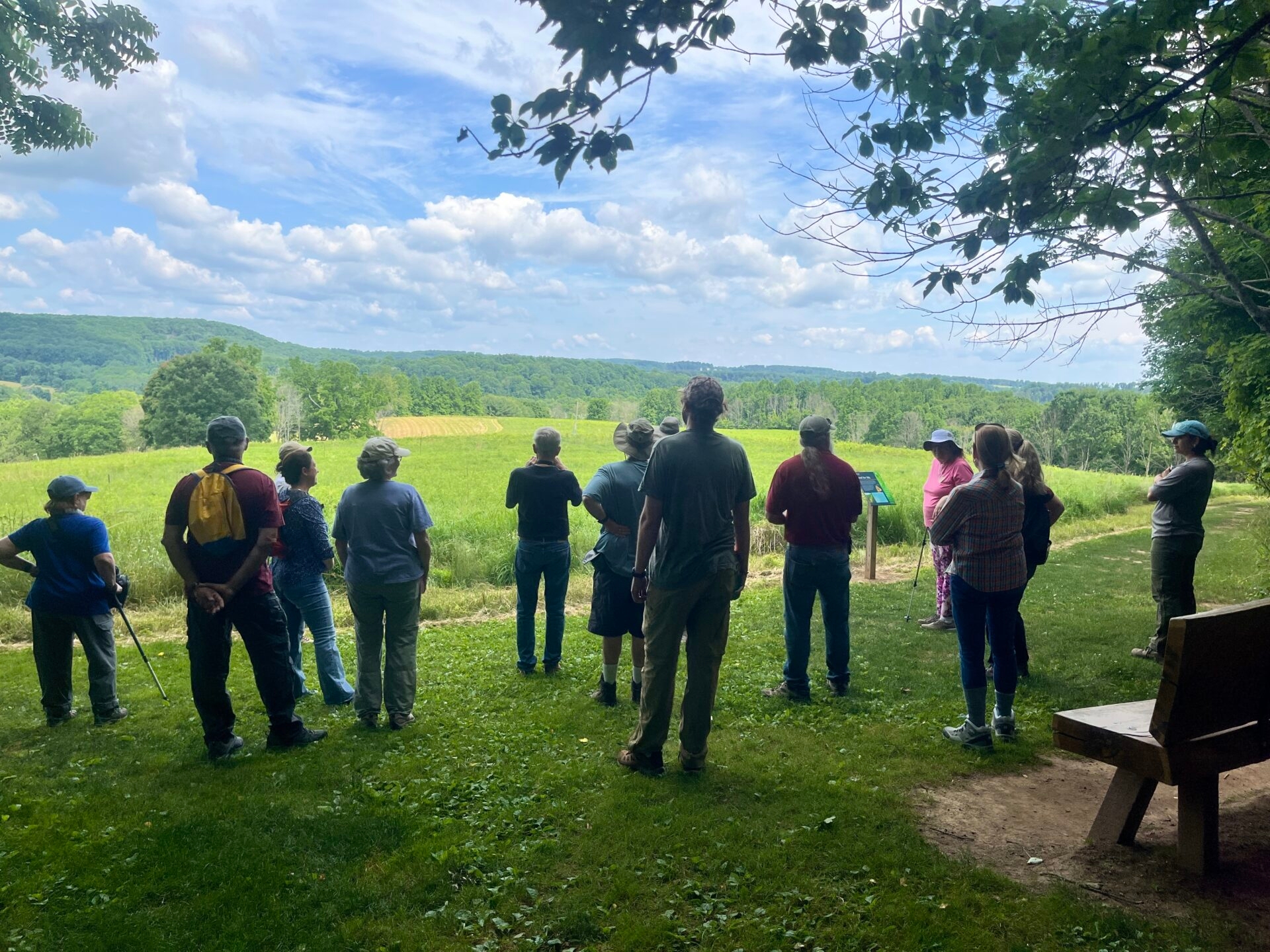 a group of people on a hillside looking out over a vista - Donors enjoying a hike and the view at Binky Lee Preserve in summer.

